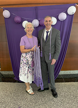 Catherine Wilson Cox holding Sigma honor cords next to former Sigma president Ric Ricciardi.