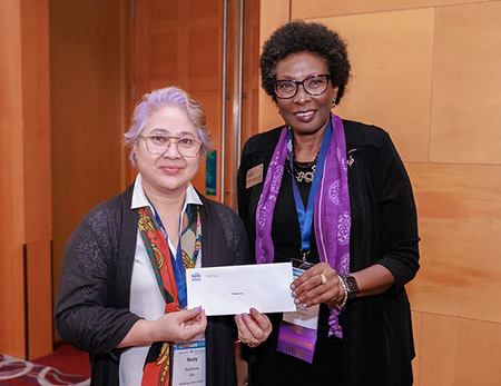 Restituta Tan, Leadership Education Grant recipient on right, with Sigma President Sandra Bibb. The two are posing with a check.