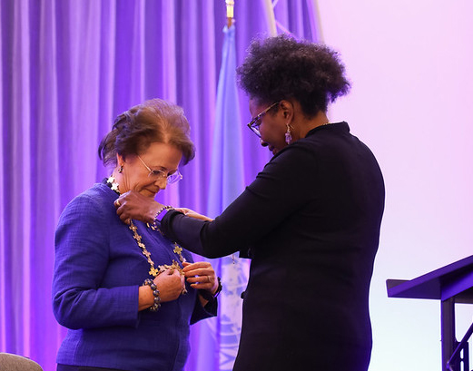 Former Sigma President Sandra Bibb helping adjust presidential chain around President Liz Westcott.